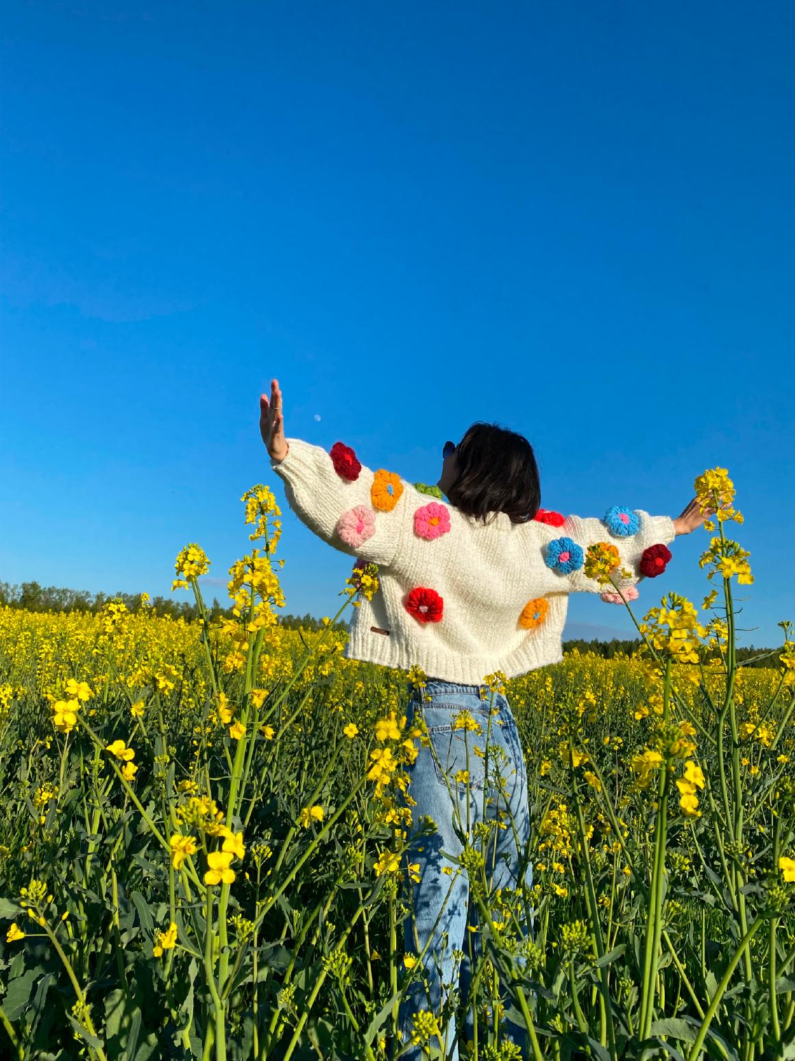 Девушка в свитере с вязаными объёмными цветами в поле