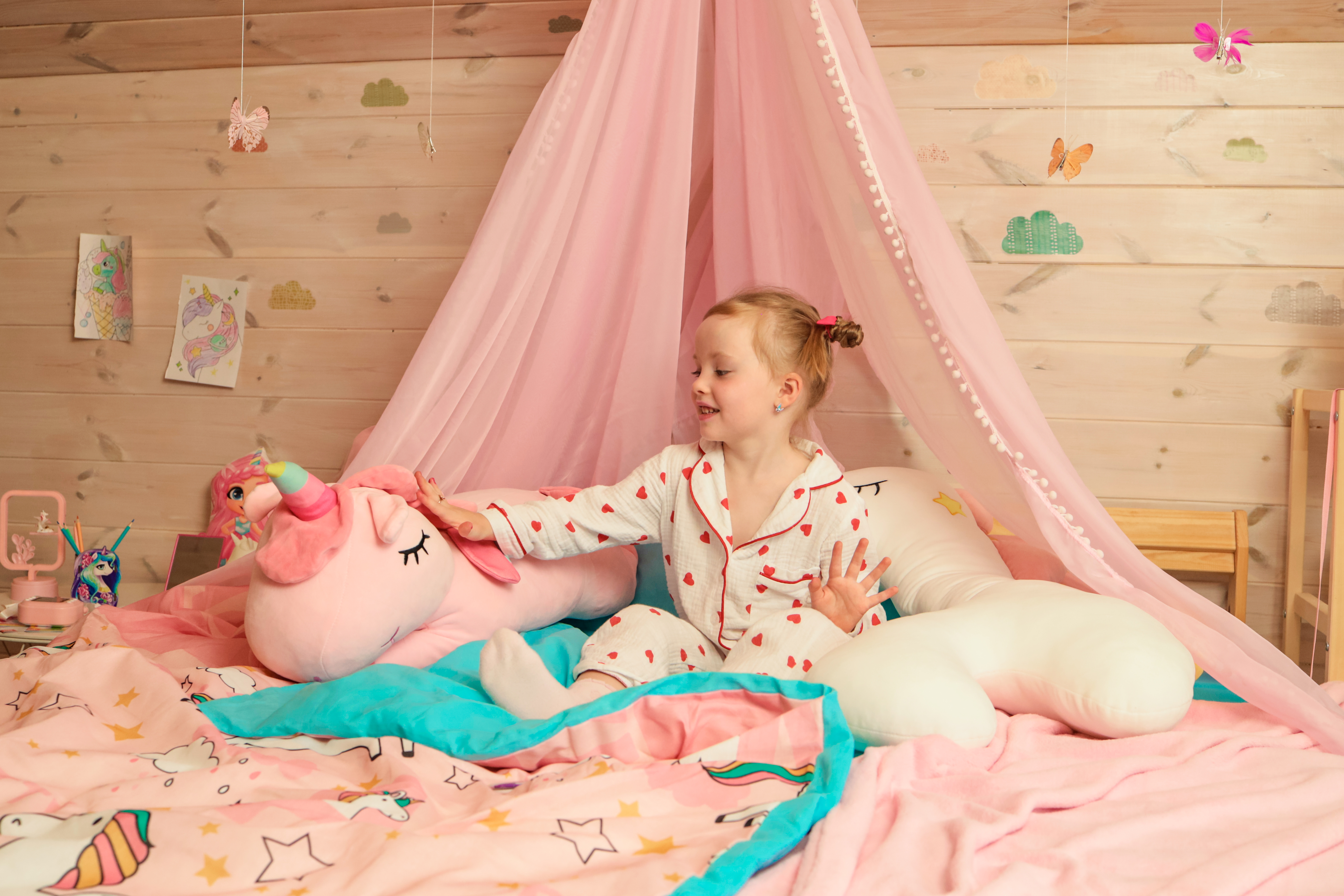 девочка на кровати с мягкой игрушкой-единорогом