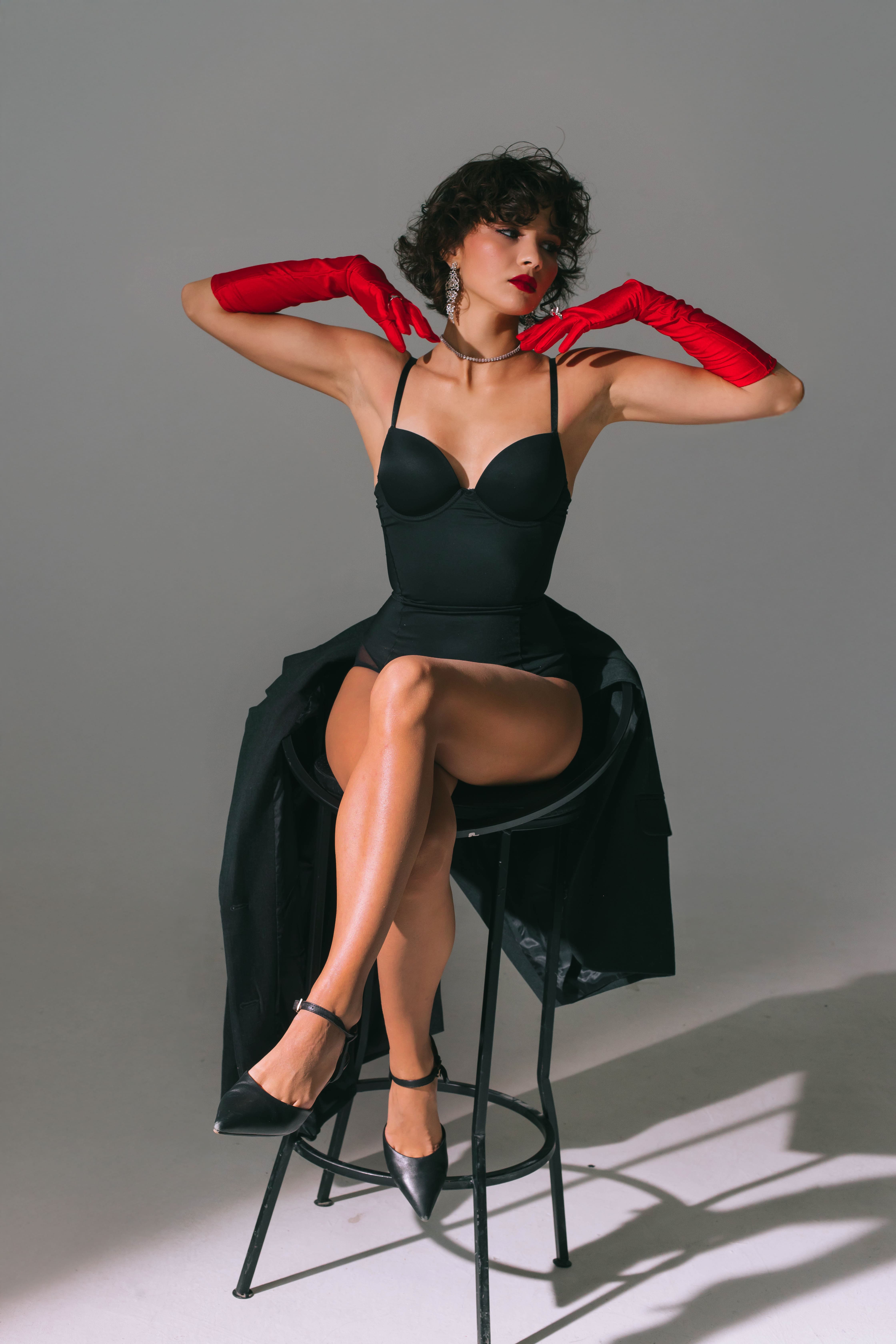 Девушка на стуле в чёрном платье и красных перчатках