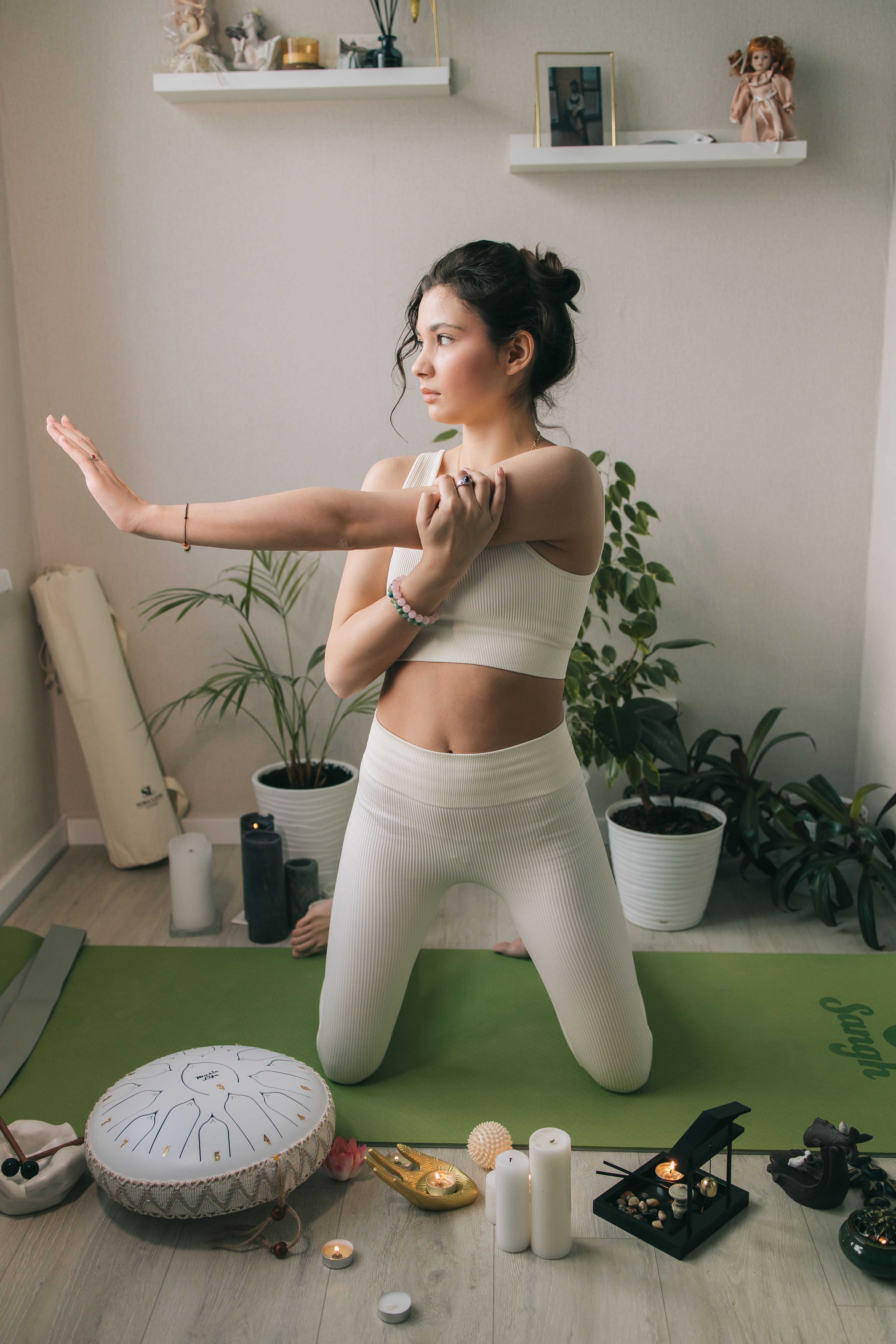 Девушка занимается йогой в белом костюме у себя дома